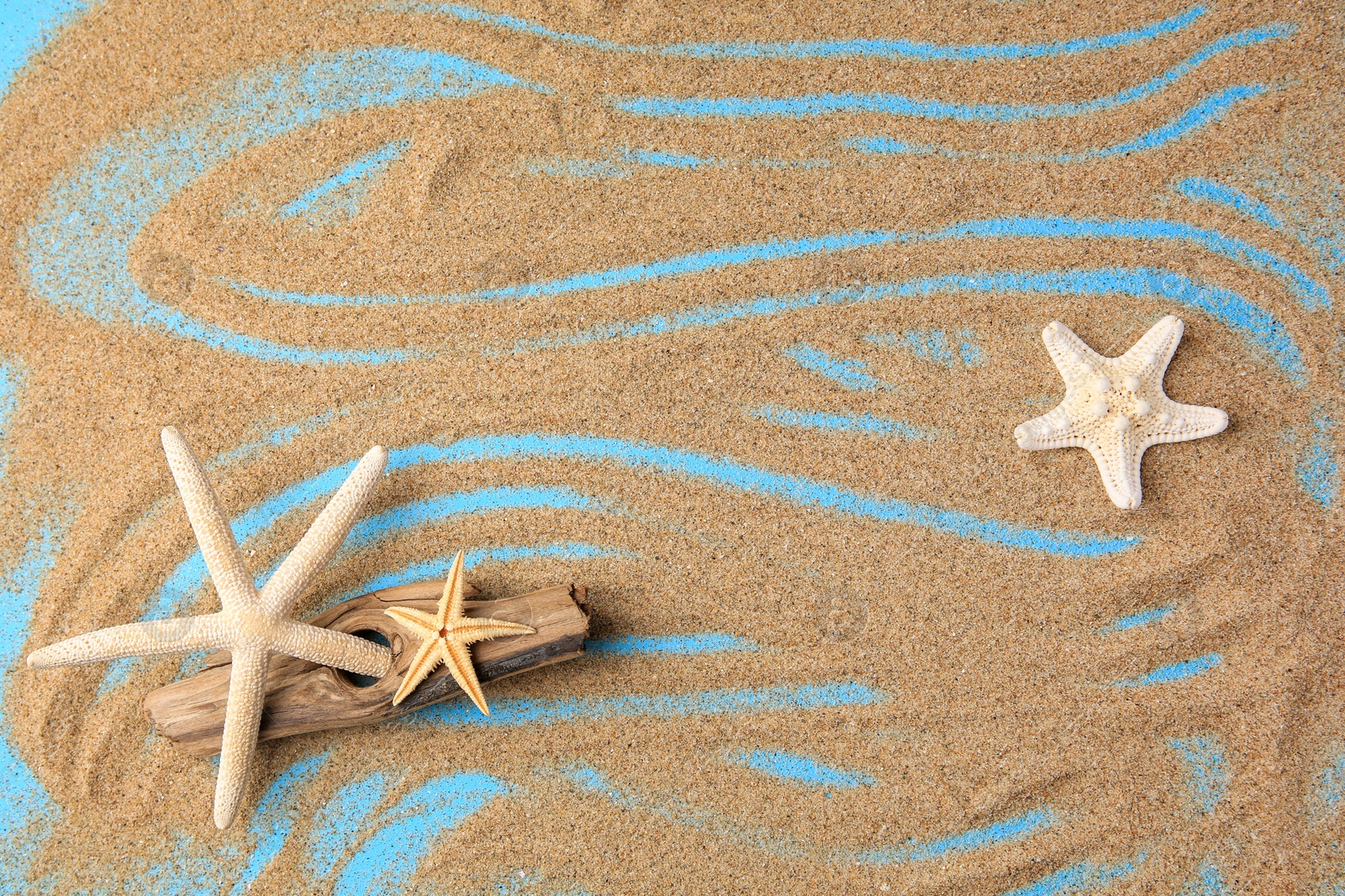 Photo of Piece of wood with beautiful starfishes and sand on blue background, flat lay. Space for text