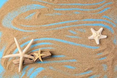 Piece of wood with beautiful starfishes and sand on blue background, flat lay. Space for text
