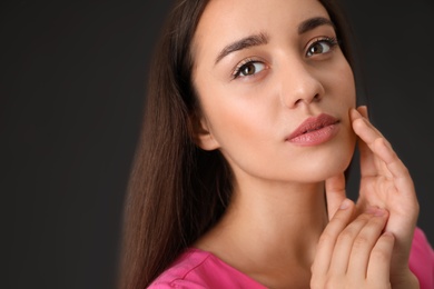 Portrait of beautiful young woman on dark grey background, closeup