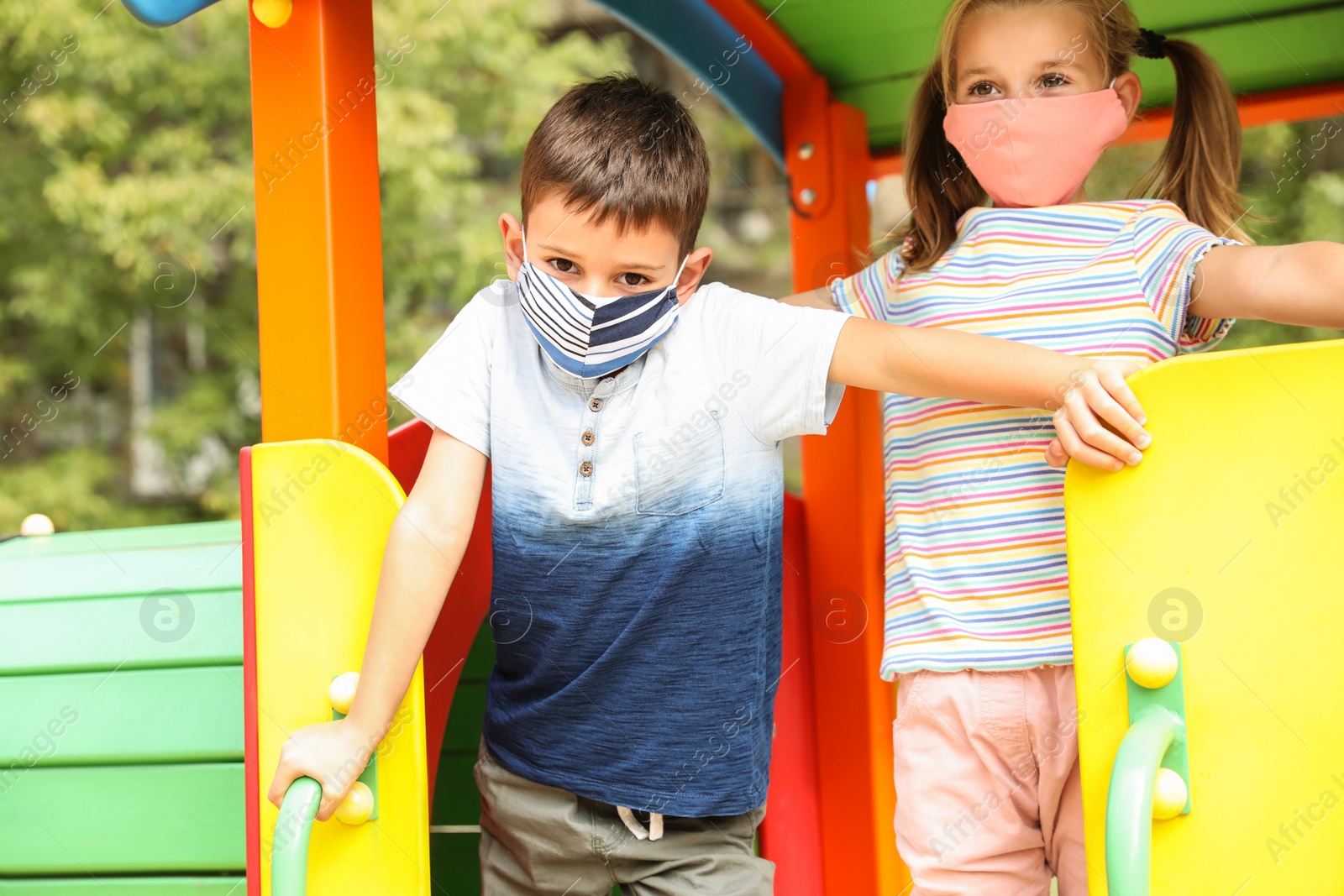 Photo of Little children with medical face masks on playground during covid-19 quarantine