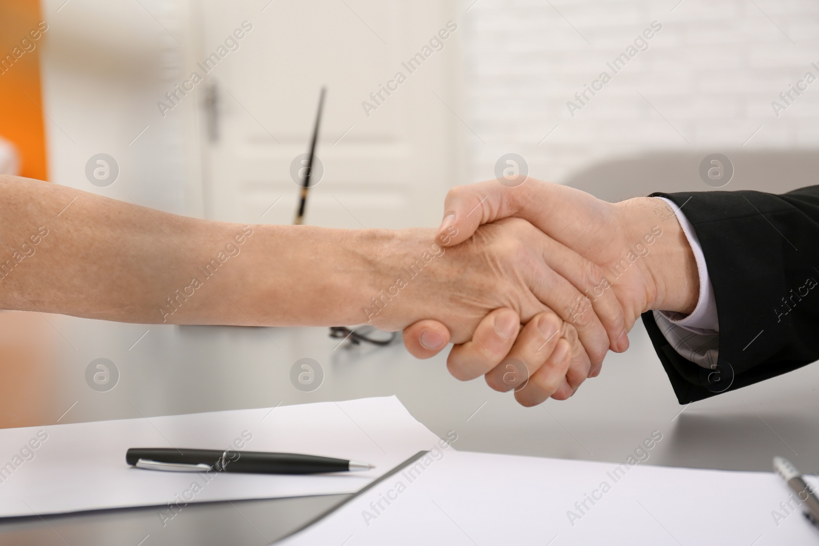 Photo of Lawyer shaking hands with client in office, closeup