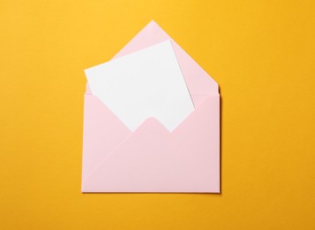 Photo of Blank sheet of paper in open letter envelope on orange background, top view