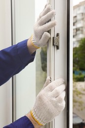 Photo of Worker putting rubber draught strip onto window indoors, closeup