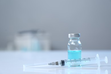 Photo of Syringe and vial on white table. Space for text