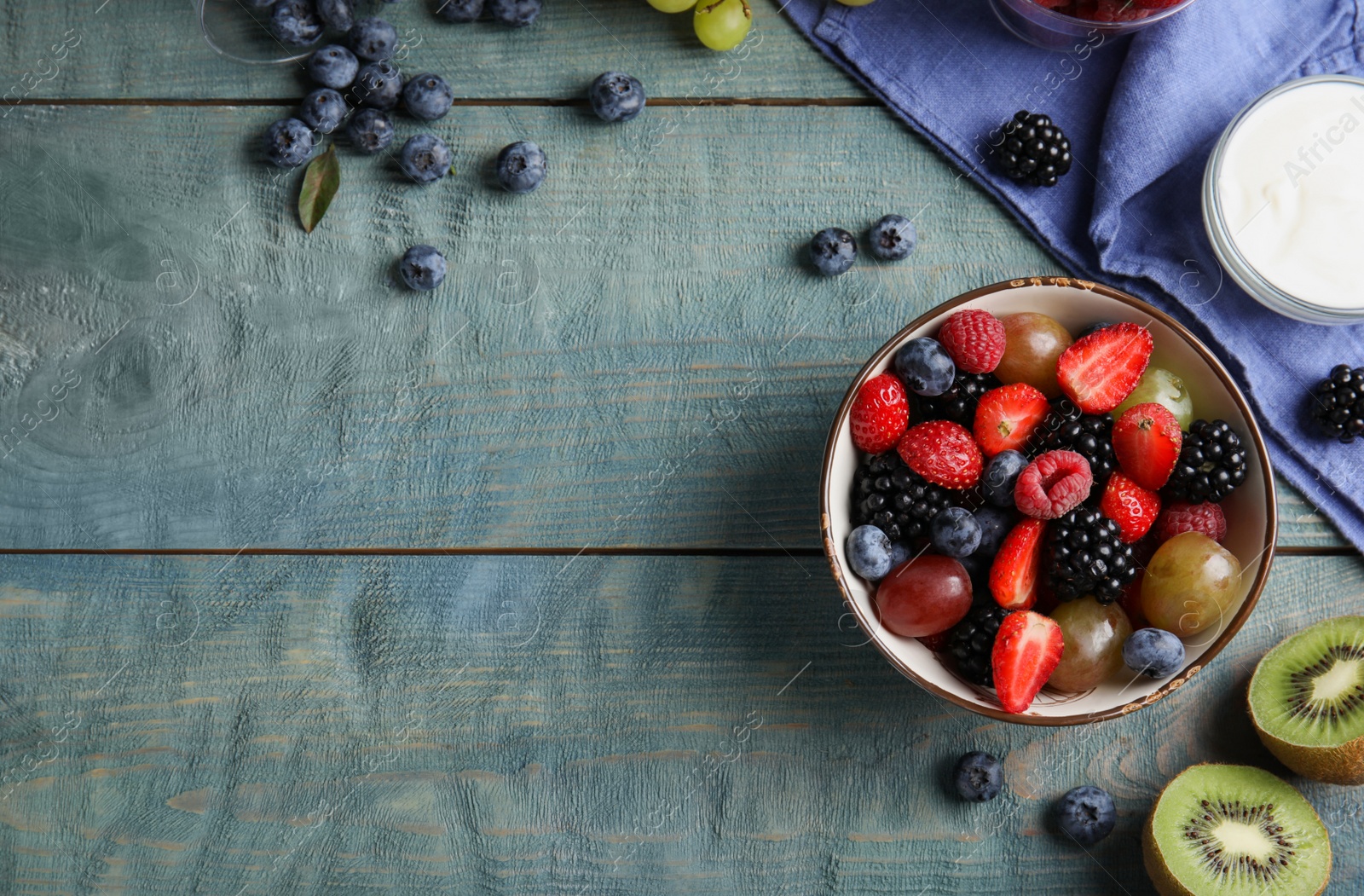 Photo of Fresh tasty fruit salad on blue wooden table, flat lay. Space for text