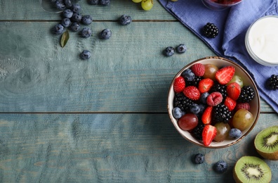 Photo of Fresh tasty fruit salad on blue wooden table, flat lay. Space for text