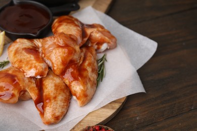 Raw marinated chicken wings and rosemary on wooden table, closeup. Space for text