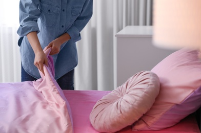 Woman making bed with new linens in children's room, closeup. Modern interior design