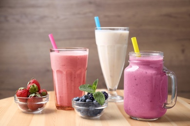Photo of Different milk shakes and berries on wooden table