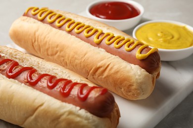 Photo of Fresh delicious hot dogs with sauces on table, closeup
