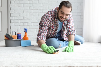 Young man cleaning carpet at home