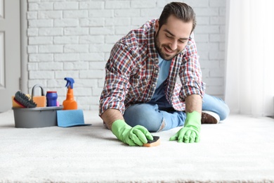 Photo of Young man cleaning carpet at home