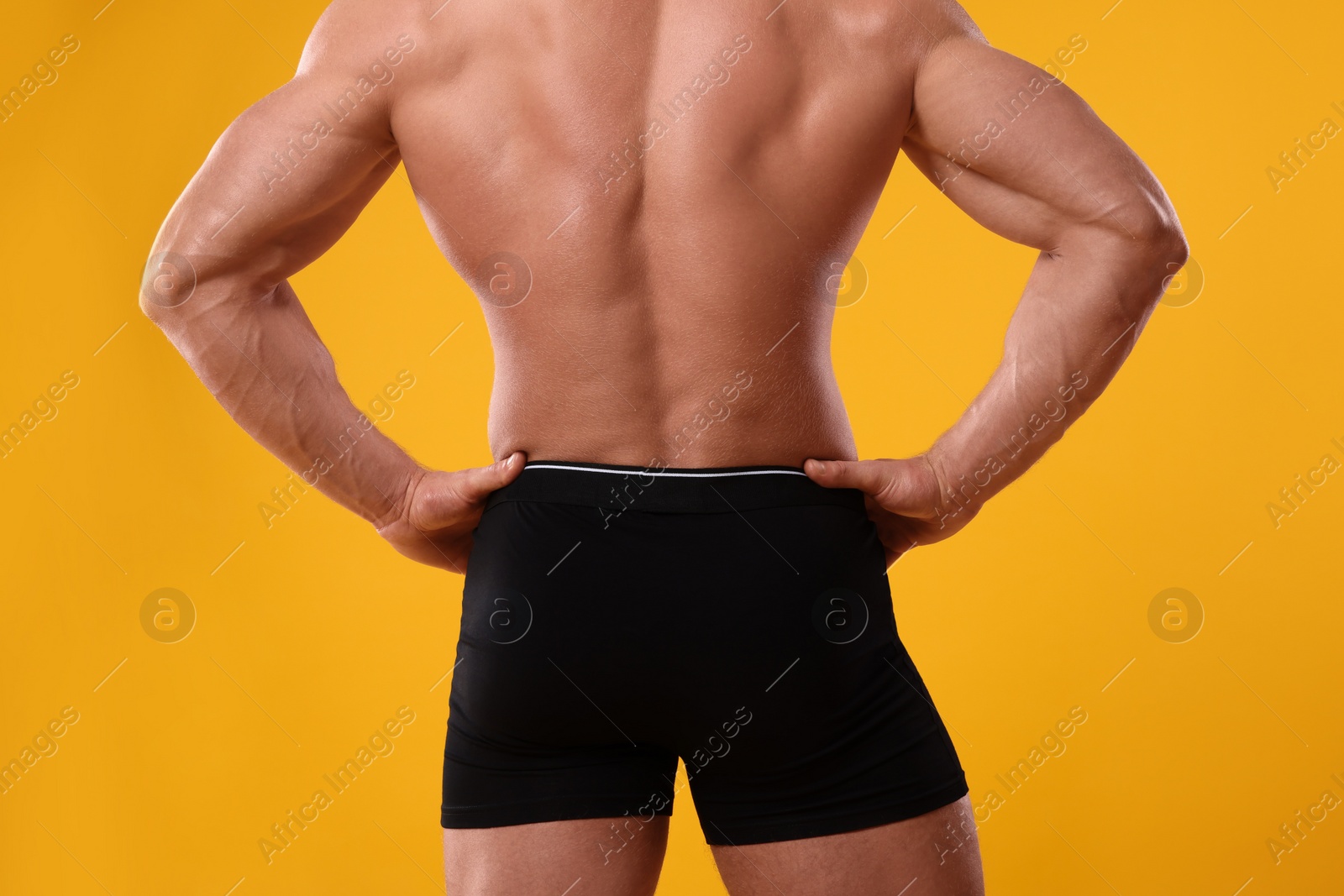 Photo of Young man is stylish black underwear on orange background, closeup