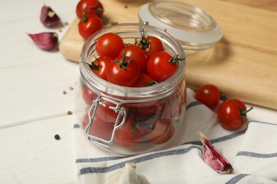Pickling jar with fresh ripe cherry tomatoes and spices on white wooden table