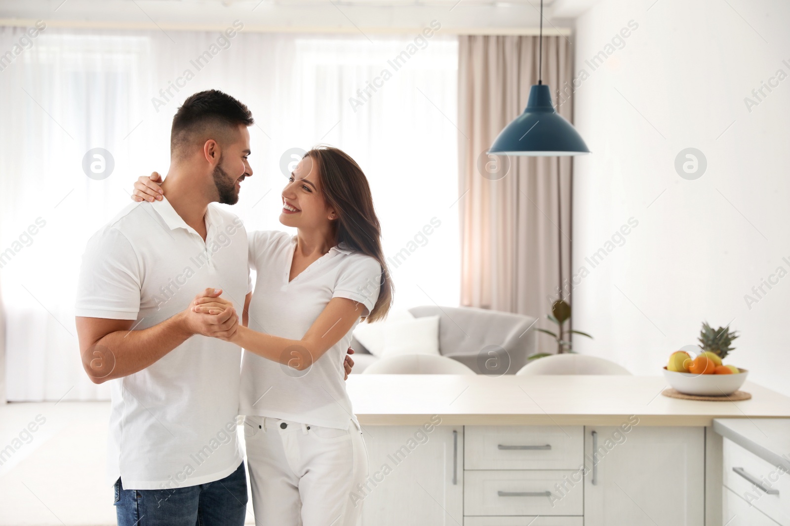 Photo of Lovely young couple dancing in kitchen at home