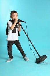 Photo of Cute funny boy with microphone on color background