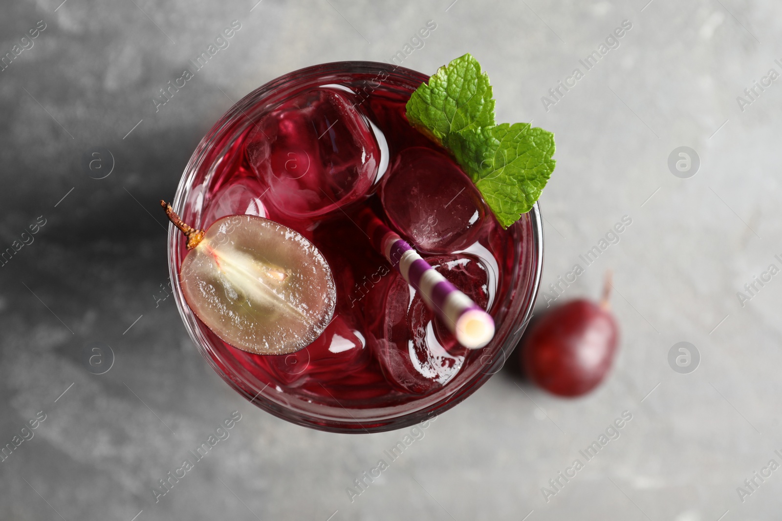 Photo of Delicious grape soda water on grey table, flat lay. Refreshing drink