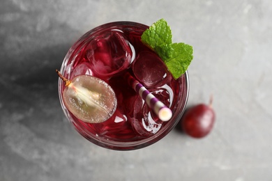 Photo of Delicious grape soda water on grey table, flat lay. Refreshing drink