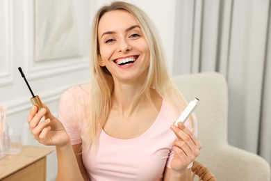 Photo of Beautiful happy woman with mascara at home