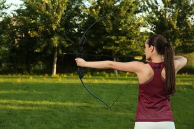 Photo of Woman with bow and arrow practicing archery in park