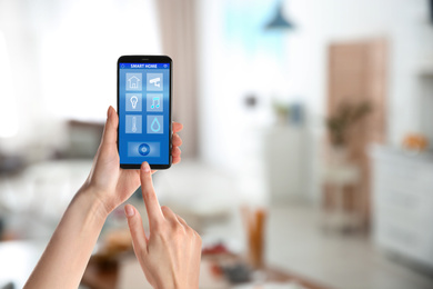 Image of Woman using phone application for controlling smart home indoors, closeup