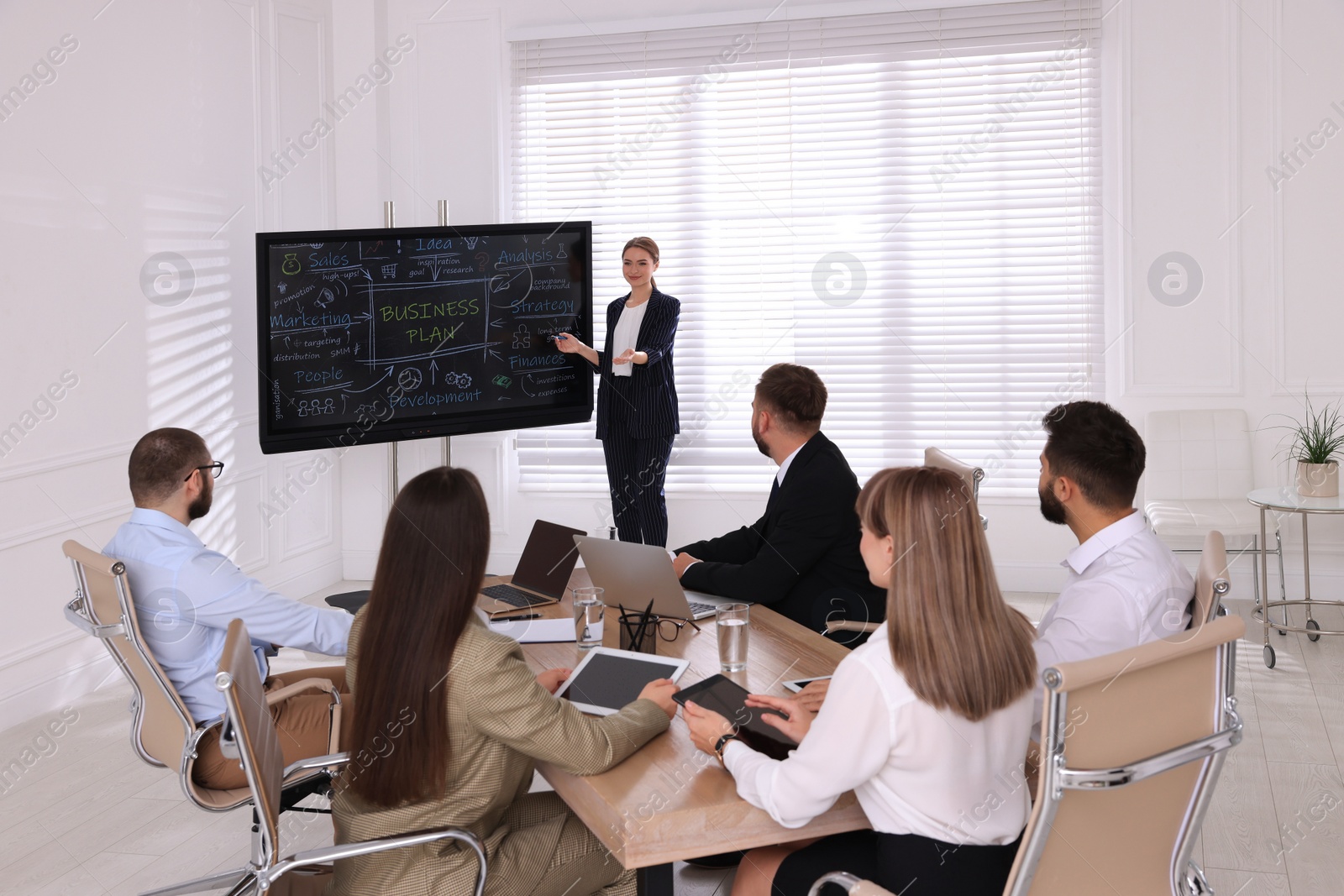 Photo of Business trainer using interactive board in meeting room during presentation