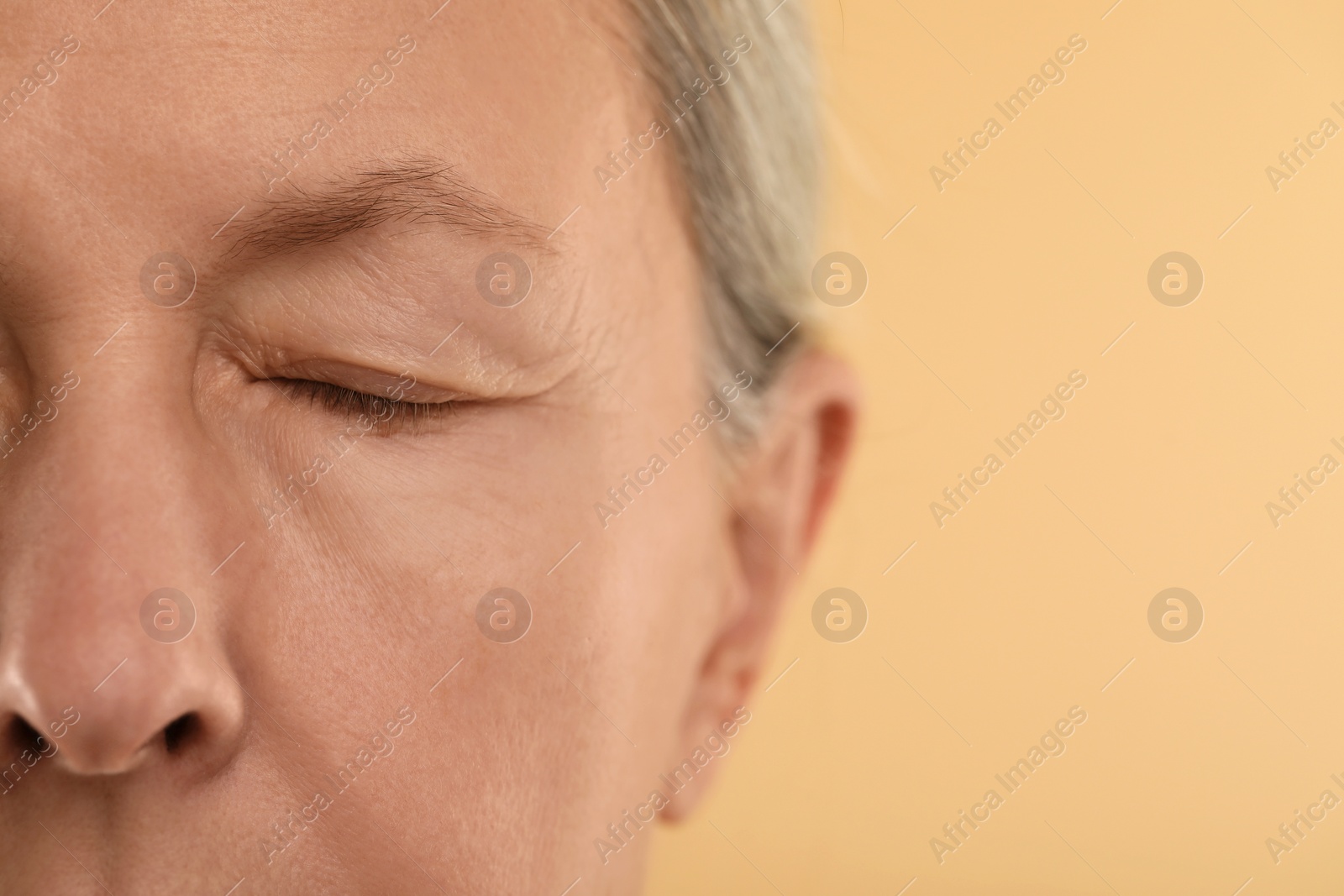 Photo of Woman with closed eyes on beige background, macro view. Space for text