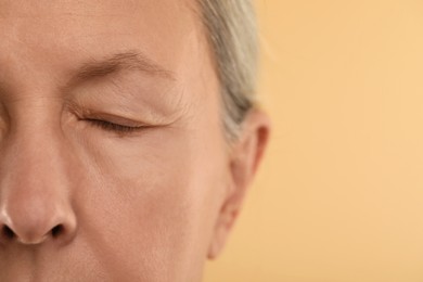 Woman with closed eyes on beige background, macro view. Space for text