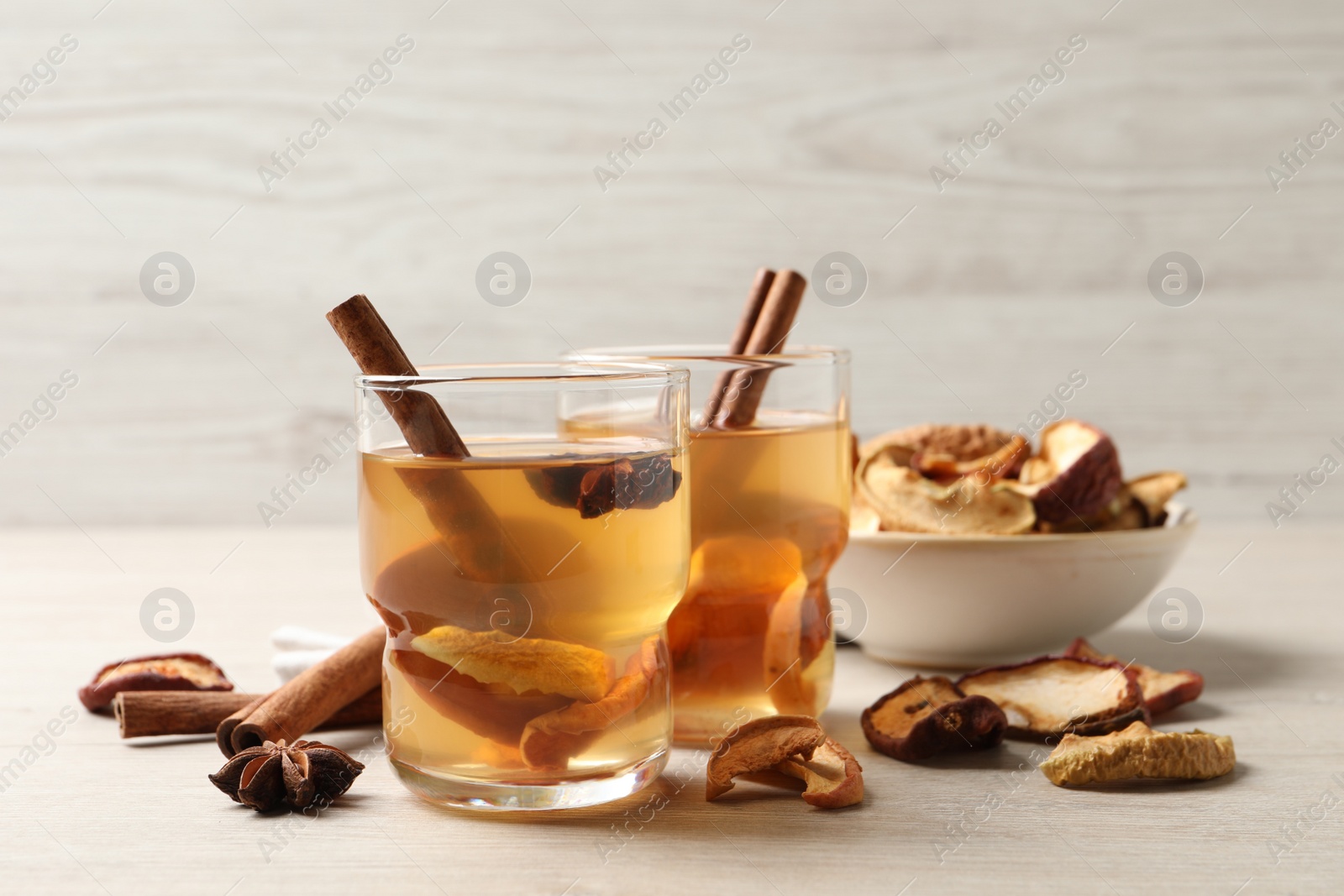 Photo of Delicious compote with dried apple slices, anise and cinnamon on white wooden table
