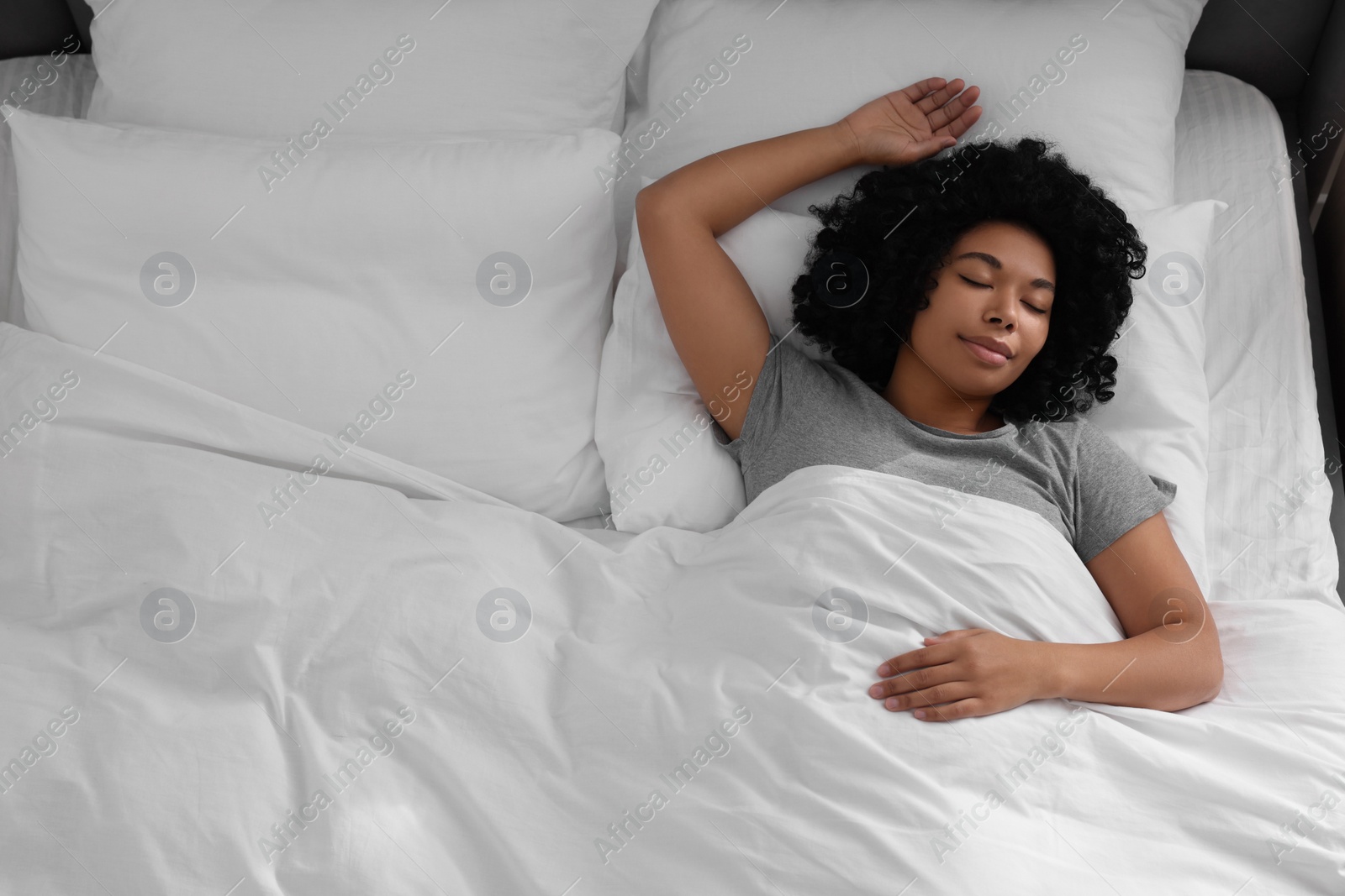 Photo of Beautiful young woman sleeping in soft bed, above view