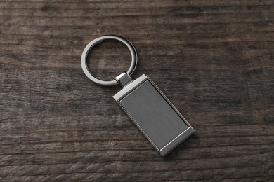 Metallic keychain on wooden background, above view