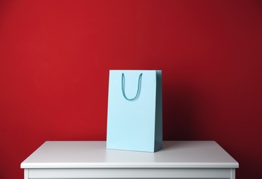 Photo of Paper shopping bag on white table against red background