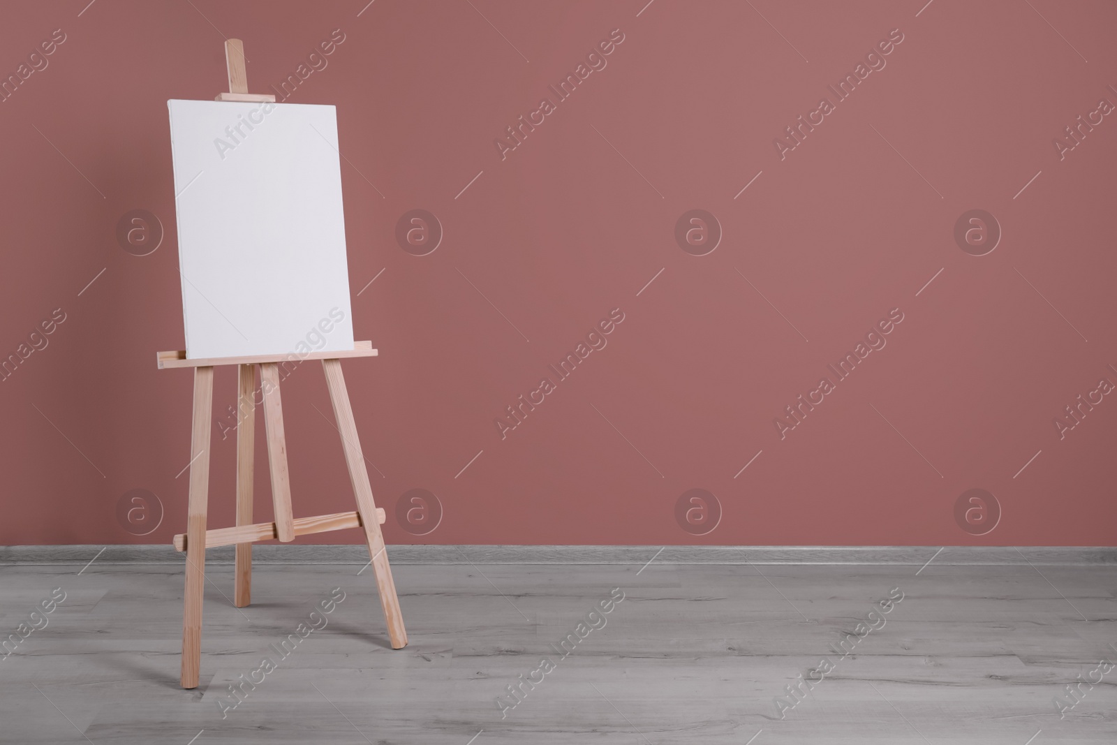 Photo of Wooden easel with blank canvas indoors. Space for text