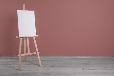 Photo of Wooden easel with blank canvas indoors. Space for text