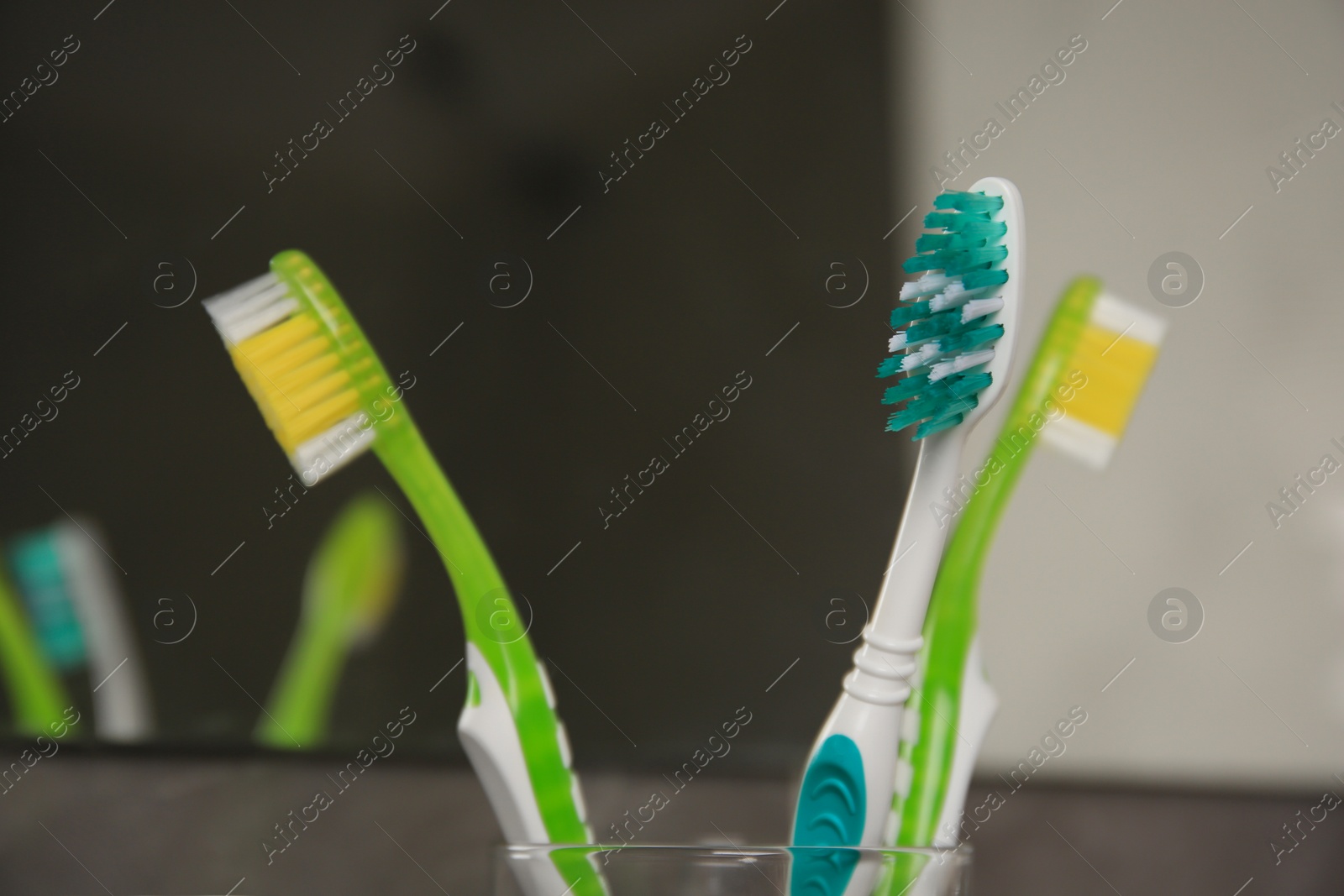 Photo of Light blue and green toothbrushes against blurred background, closeup