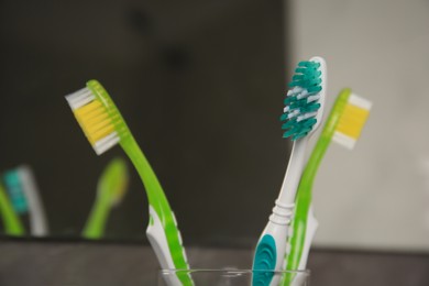 Light blue and green toothbrushes against blurred background, closeup