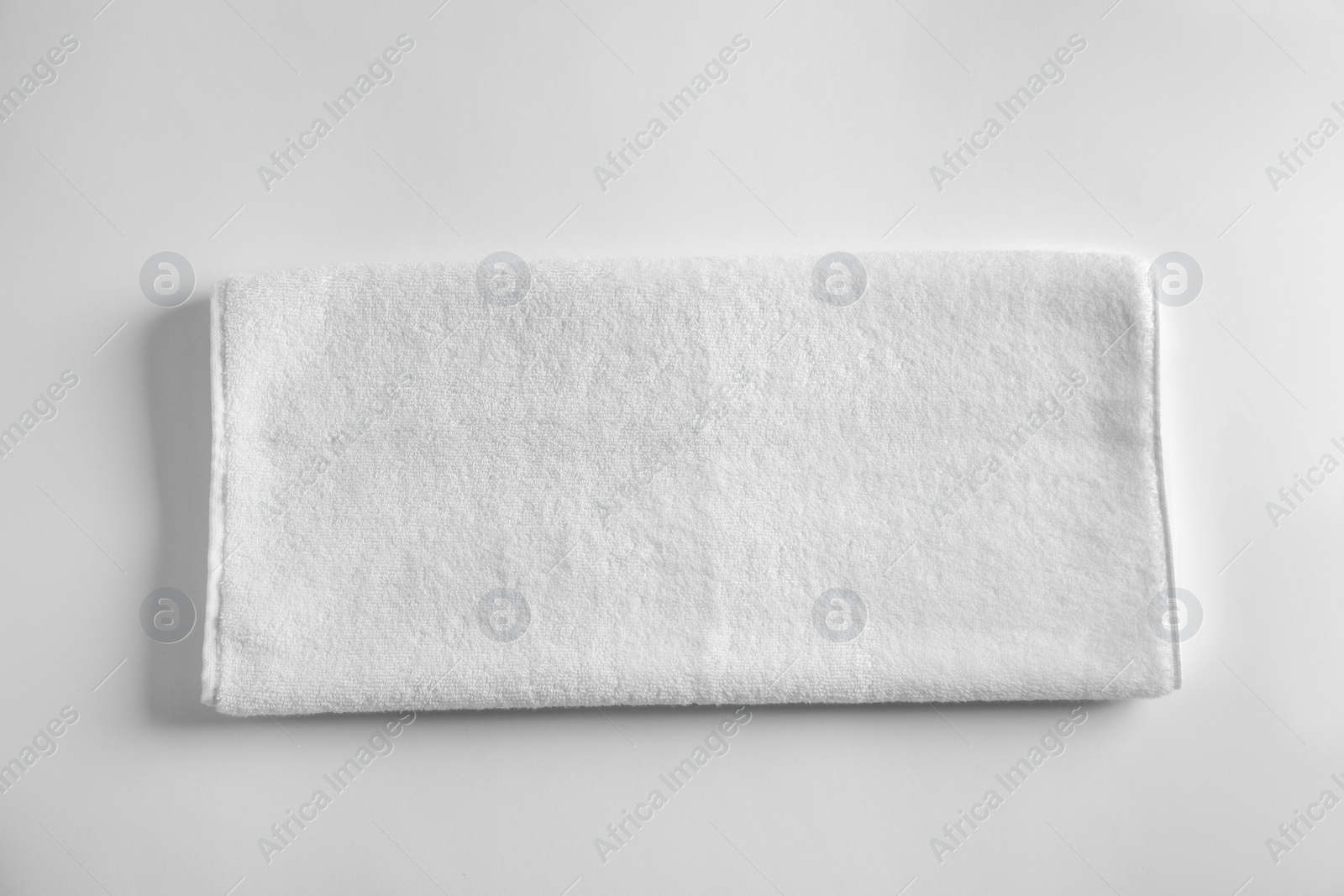 Photo of Folded soft terry towel on light background, top view