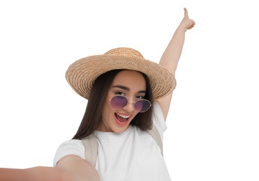 Smiling young woman in sunglasses and straw hat taking selfie on white background