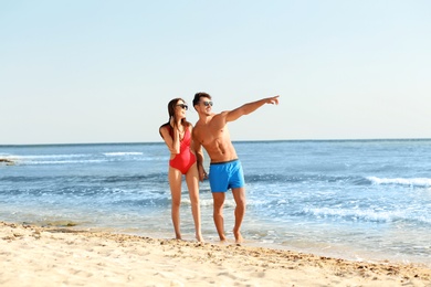 Happy young couple walking together on beach