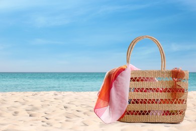 Bag with accessories on sunny ocean beach, space for text. Summer vacation