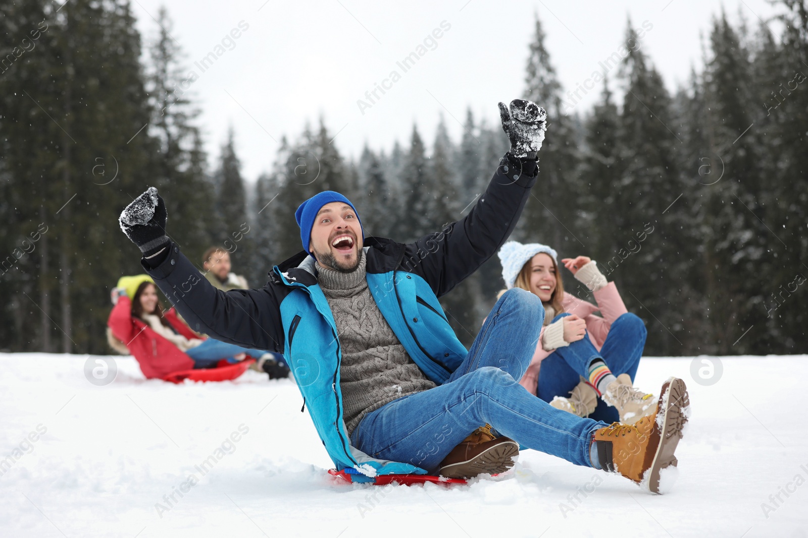 Photo of Happy friends sliding on sleds outdoors. Winter vacation