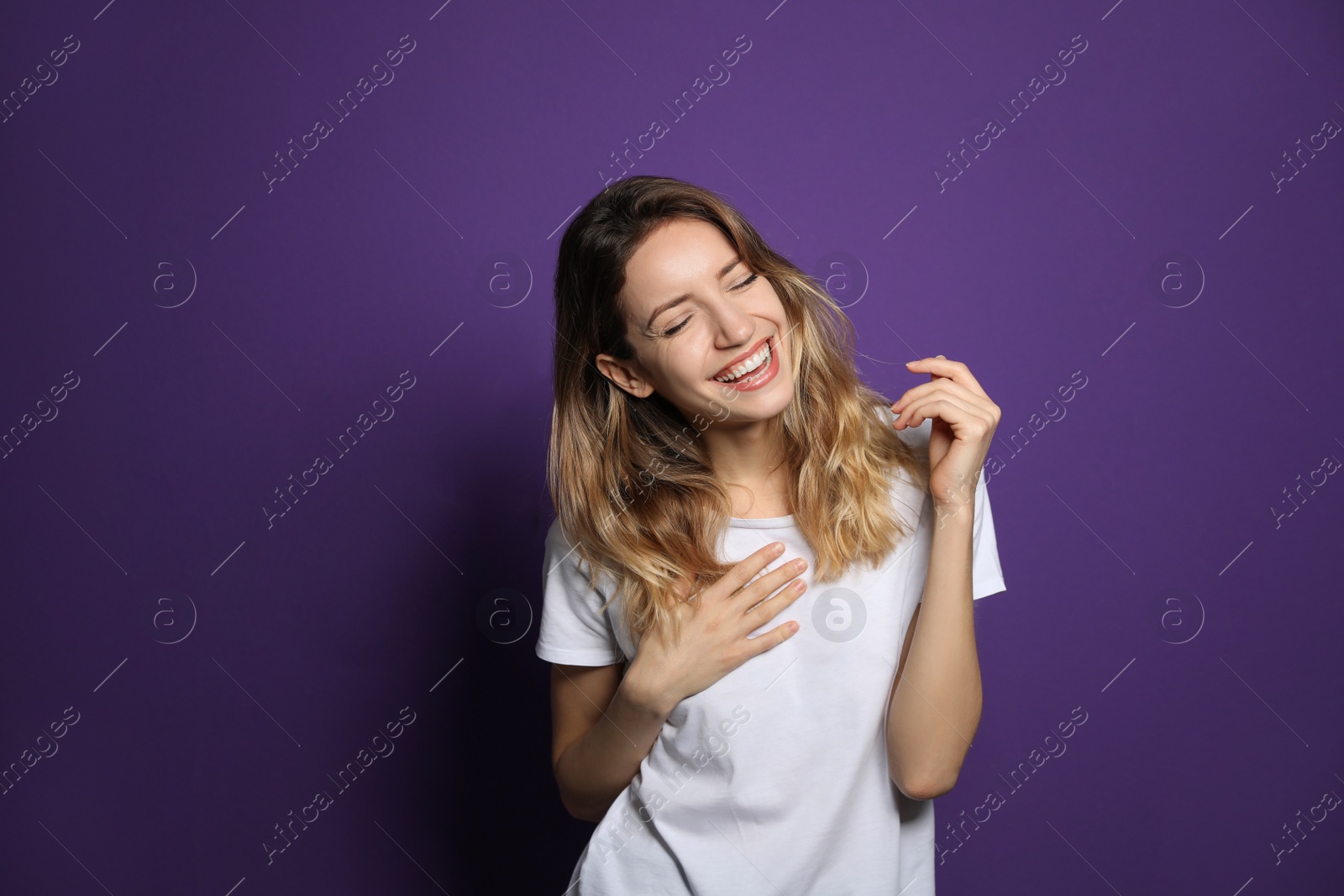 Photo of Cheerful young woman laughing on violet background