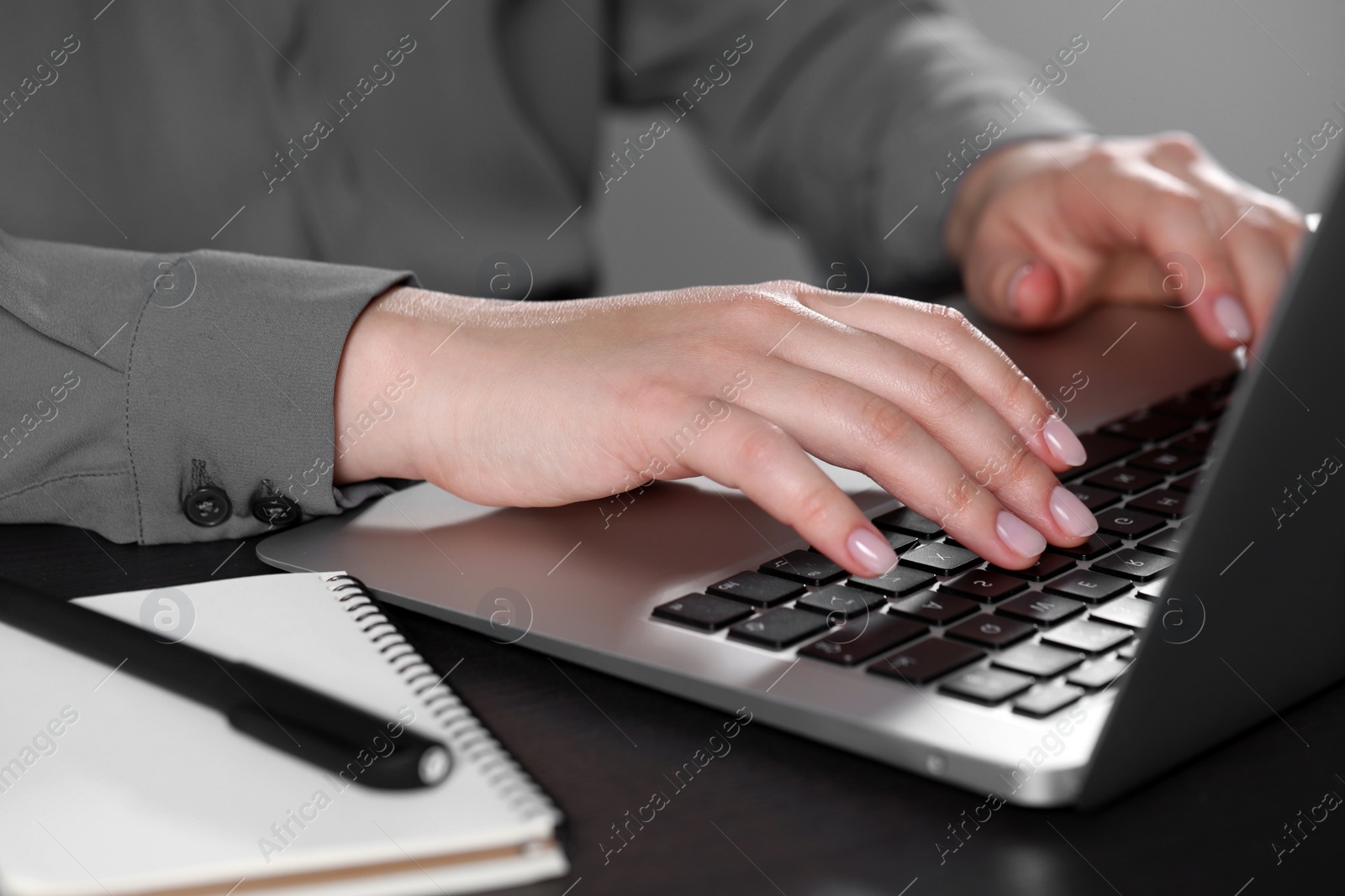 Photo of Woman typing on laptop at table, closeup. Electronic document management