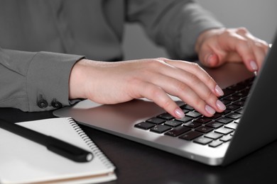 Woman typing on laptop at table, closeup. Electronic document management