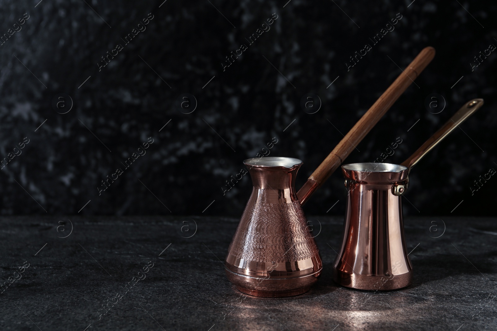 Photo of Beautiful copper turkish coffee pots on grey table. Space for text