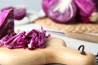 Photo of Shredded red cabbage and cutting board on kitchen table, closeup