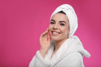 Photo of Happy young woman in bathrobe with towel on head against pink background, space for text. Washing hair