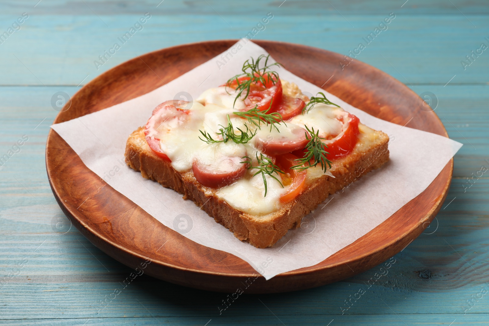 Photo of Tasty pizza toast with cheese, tomato and dill on light blue wooden table