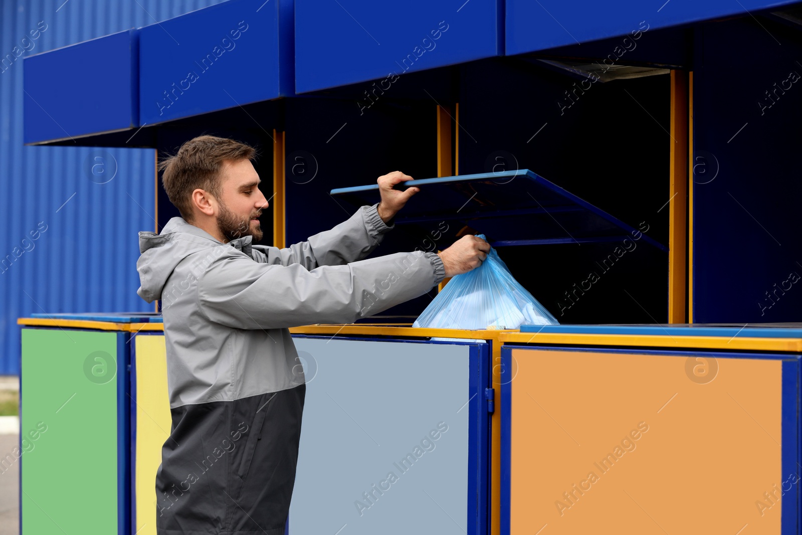 Photo of Man throwing garbage into bin at recycling point outdoors