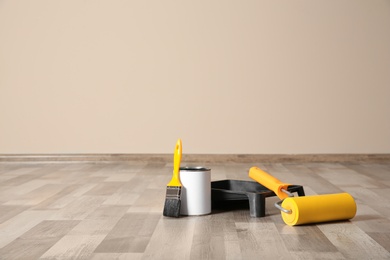 Can of paint and decorator tools on wooden floor indoors. Space for text